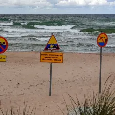 Na plaży widać znaki zakazu kąpieli i ostrzeżenia o budowlach hydrotechnicznych. Żółta flaga na plaży oznacza, że kąpiel jest dozwolona, ale należy zachować ostrożność.