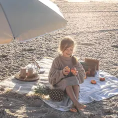Dziewczynka na plaży pod parasolem, jedząca owoce. Idealny przykład, co zabrać na wakacje nad morze z dzieckiem: koc, owoce, ananas i arbuz.