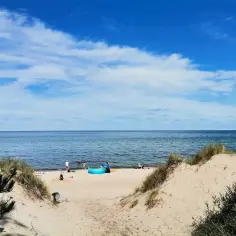 Piękna plaża w Rusinowie, idealne miejsce na letnie atrakcje. Rodziny kąpią się w morzu, dzieci bawią się na piasku.