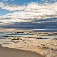 Piękne fale na plaży w Krynicy Morskiej. Pogoda w lipcu zachwyca, chmury na niebie tworzą malowniczy widok.