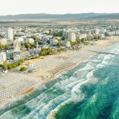 Widok na plażę i kurort z hotelami, karuzelą i morzem. To dowód, że Bułgaria ma dostęp do morza.