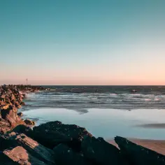 Skały na plaży o zachodzie słońca, fale na morzu. Czy Morze Czarne jest czyste? Woda wygląda na czystą, a niebo jest błękitne.