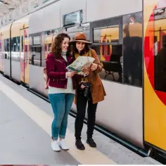Dwie kobiety z mapą na dworcu, planują gdzie najszybciej nad morze z Poznania.