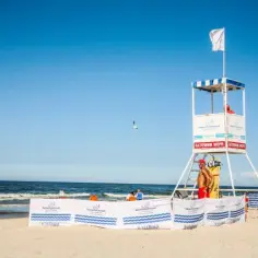 Ratownik na plaży czeka na sygnał. Biała flaga co oznacza? Bezpieczeństwo i spokój, idealne warunki do kąpieli.