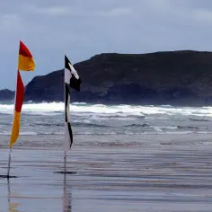 Dwie flagi na plaży: czerwono-żółta i czarno-biała szachownica. Czarna flaga nad morzem oznacza, że kąpiel jest zabroniona.