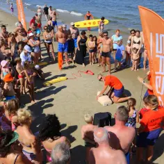 Swarzewo plaża: ratowniczka demonstruje resuscytację na fantomie, zgromadzeni ludzie obserwują.