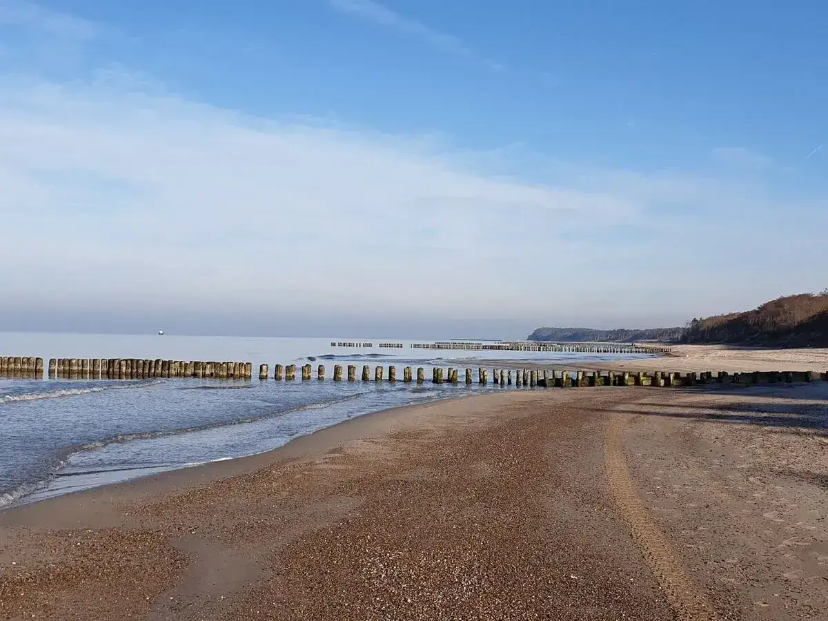 Spokojna plaża w Rusinowie z drewnianymi falochronami. Idealne miejsce na relaks i podziwianie widoków. Rusinowo atrakcje to cisza i piękno natury.