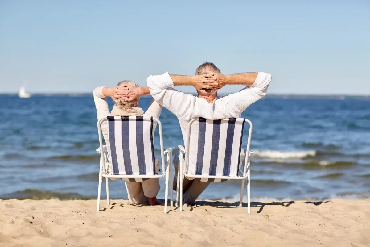 Para seniorów odpoczywa na plaży, ciesząc się słońcem i morzem. Idealne tanie wczasy dla seniora nad morzem.