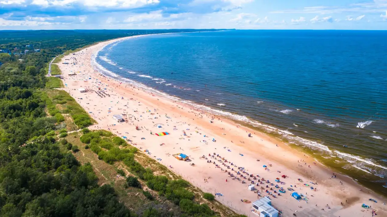 Szeroka, piaszczysta plaża pełna ludzi, idealna na wakacje. To jedno z najlepszych miejsc nad morzem, gdzie można odpocząć i cieszyć się słońcem.